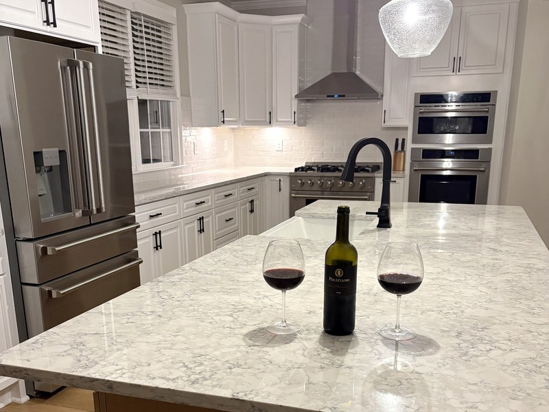 Custom white kitchen with a warm-wood island, natural-stone counters, and a professional gas range: a RYMAC kitchen remodel in Milton, GA.