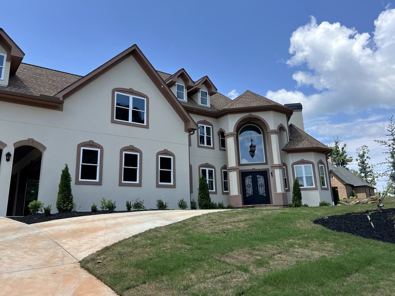 Finished, landscaped front elevation of a large custom stucco home with an arched entry: a 5,876 sq ft RYMAC custom home in Gainesville, GA.